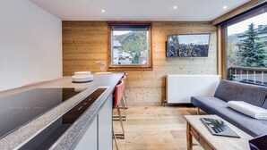 A modern kitchen with a large island, wooden walls, and a view of a mountain landscape.