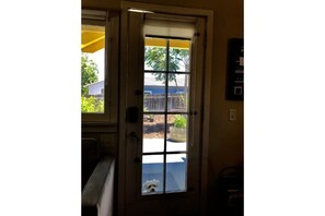 Enter a room with a door leading to an outdoor area, featuring a glass panel and metal handle.