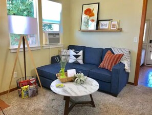Relax in this inviting living room with a sofa, coffee table, and lamp, surrounded by a potted plant, decorative vase, and framed artwork.