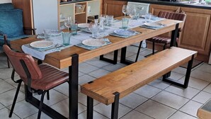 Un comedor con una mesa de madera dispuesta para cuatro personas, rodeada de sillas y un banco.