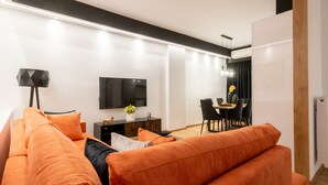 Un salon moderne comprenant un canapé, un téléviseur à écran plat et un coin repas avec des chaises et une table.