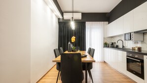 Une cuisine moderne avec des armoires blanches, un plan de travail noir et un four encastré.