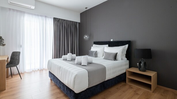 Une chambre d’hôtel moderne avec un grand lit, un bureau et une chaise.