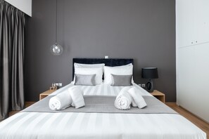 Une chambre d’hôtel moderne avec un grand lit, une table de chevet, une lampe et un luminaire suspendu.