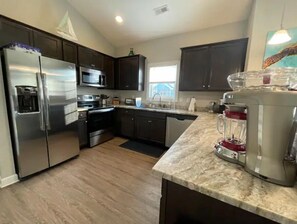 Enjoy cooking in this well-equipped kitchen with a stainless steel refrigerator, microwave, sink, and blender.