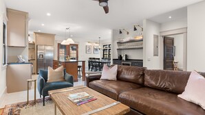 A modern living room with a brown leather sofa, a blue armchair, and a wooden coffee table.