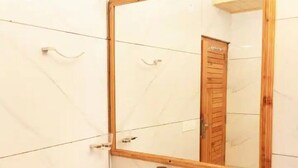 Un baño con azulejos blancos, una puerta de madera y un espejo con marco de madera.