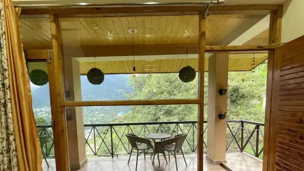 A wooden-framed room with a balcony, a table, and chairs. - Spacious Wooden Room w/ Attic Olive Manali Cottage (Manali)