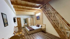 A bedroom with a wooden bed, a wooden chair, a wooden desk, and a wooden staircase. - Spacious Wooden Room w/ Attic Olive Manali Cottage (Manali)