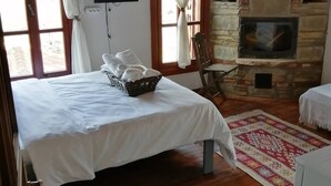 Een hotelkamer met een bed, een televisie, een stenen openhaard en een raam met gordijnen.