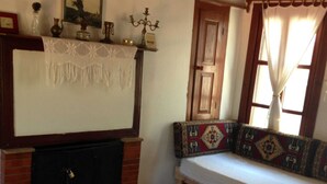 Een gezellige kamer met een open haard, een bank met gestreepte kussens en een tafel met een mand vol opgerolde handdoeken.