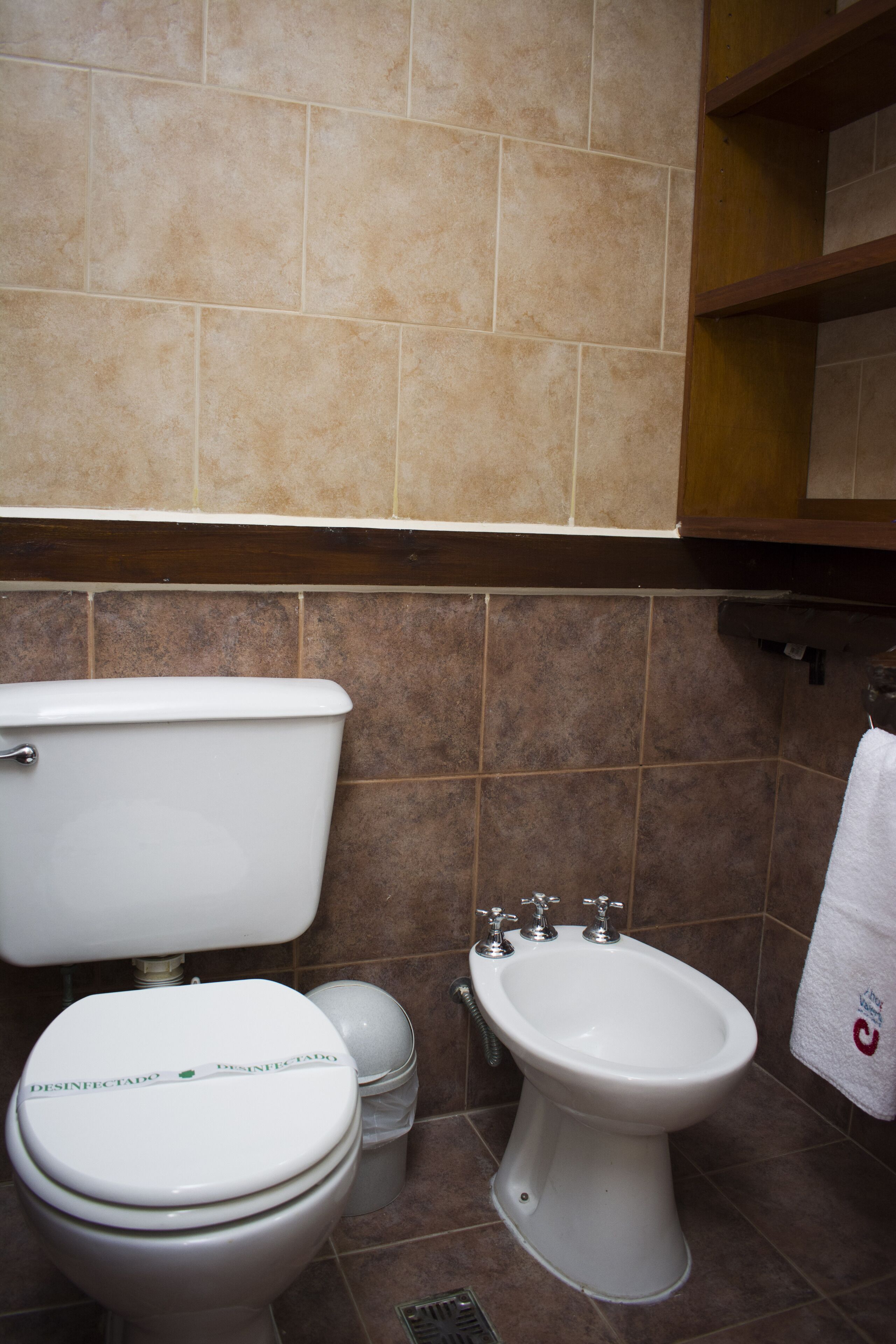 Un baño con inodoro, bidé y un cubo de basura.