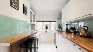 Une cuisine moderne avec des meubles blancs, un plan de travail en bois et une bouilloire.