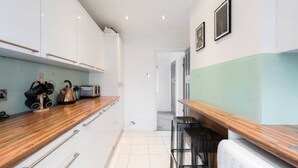 Une cuisine moderne avec des meubles blancs, un plan de travail en bois et une machine à café.