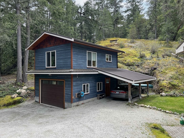 A two-story house with a garage, a covered porch, and a car parked in the driveway.
