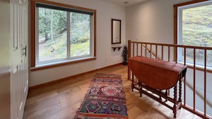 A spacious room with large windows, a wooden bench, and a colorful rug. - Modern studio. (Salt Spring Island)