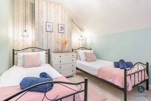 Ein Schlafzimmer mit zwei Betten, einem Schminktisch und einem an der Wand befestigten Regal mit Dekoration.
