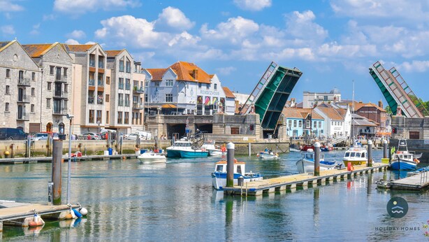 Un puerto deportivo con barcos amarrados, un puente y edificios con balcones.