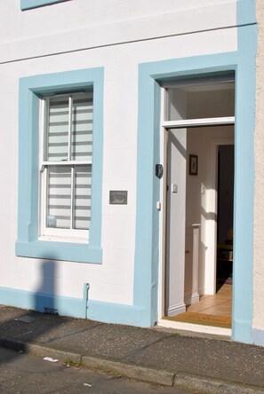 A building with a white exterior and blue trim around the windows and door. - Sea Whisper- lovely home in charming village (Pittenweem)
