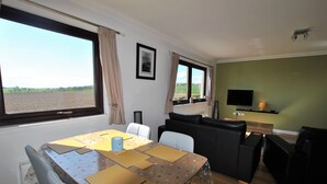 Ein Zimmer mit Esstisch, Stühlen, einer Couch und einem Fernseher.