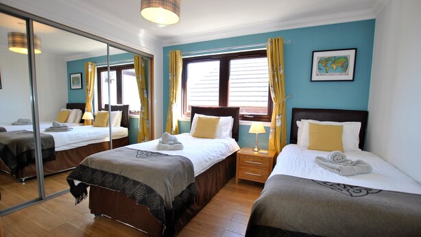 Ein Hotelzimmer mit zwei Betten, einem großen Spiegel, einer Weltkarte an der Wand und einem Holzboden.