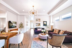 A spacious living room with a wooden coffee table, a purple sofa, and a chandelier.