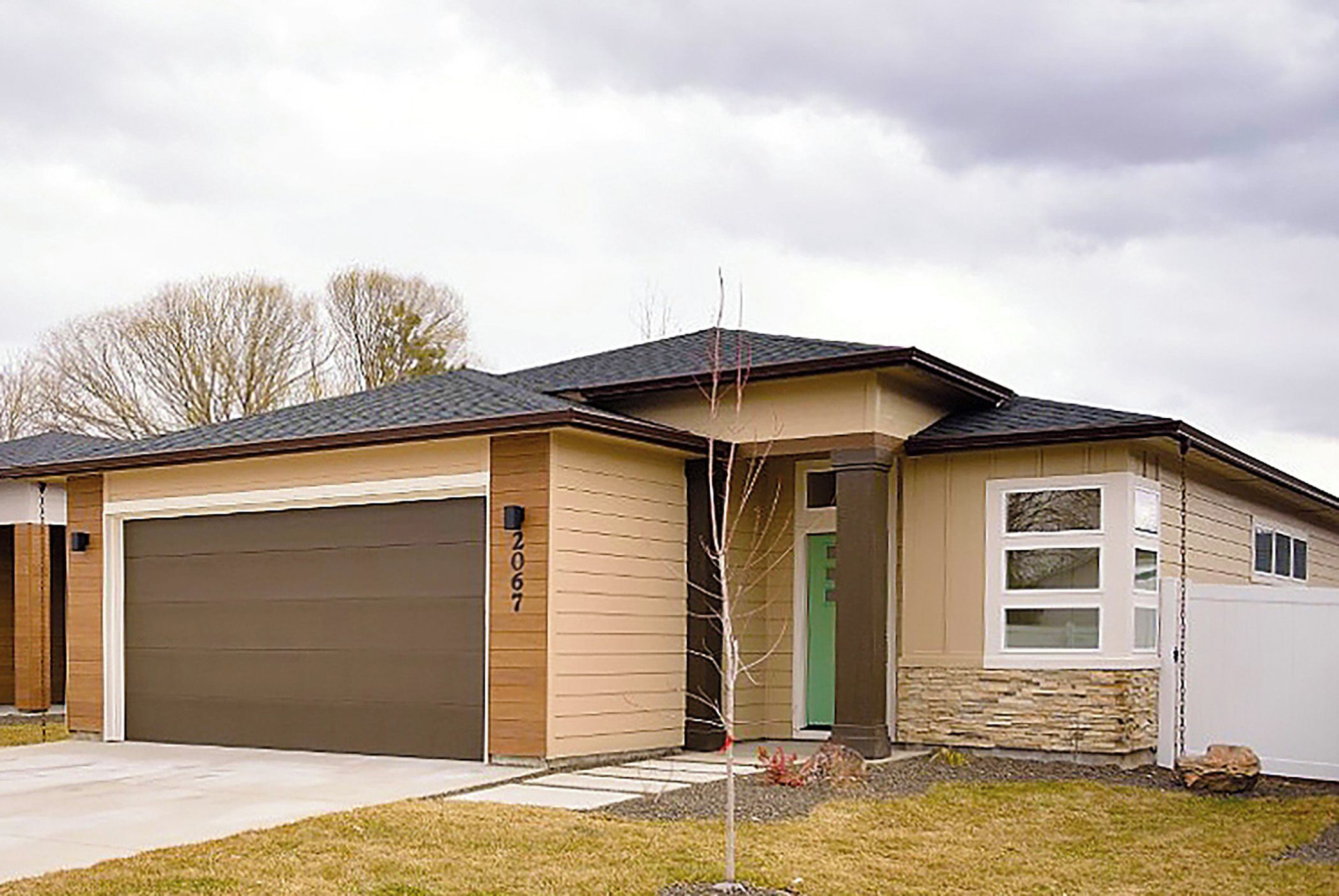 Einbungalow mit Garage, Eingangstür und kleiner Veranda.