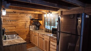 A compact kitchen with wooden cabinets, a stainless steel refrigerator, and a coffee maker.