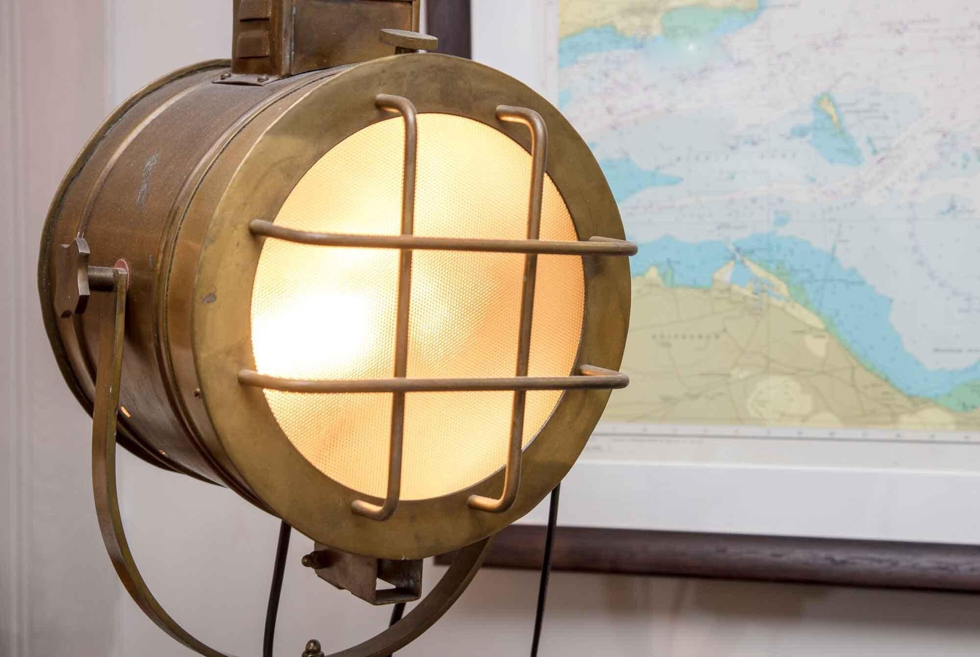 A brass lantern with a grid design, mounted on a wall with a map in the background.