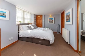 Un dormitorio con cama, radiador y ventana con persianas.