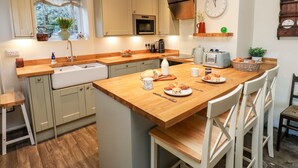 Une cuisine moderne avec des plans de travail en bois, un évier, un four à micro-ondes et une horloge au mur.
