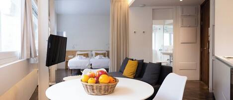 Une chambre d’hôtel moderne comprenant un coin repas, un canapé, une télévision et un coin cuisine.