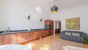 A modern kitchen with wooden cabinets, a marble countertop, and a built-in oven. - Stylish 2BD Victorian Home near Holland Park (London)
