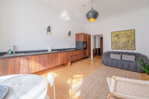 A modern kitchen with wooden cabinets, a marble countertop, and a built-in oven. - Stylish 2BD Victorian Home near Holland Park (London)