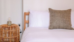 A bed with white bedding, a wooden headboard, and a textured pillow. - Stylish 2BD Victorian Home near Holland Park (London)