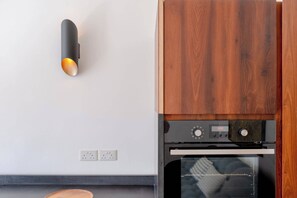 Uma cozinha com forno embutido, luminária fixada na parede e armário de madeira.