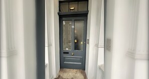 A narrow hallway with a dark blue door marked with the number 96, flanked by white columns. - Stylish 2BD Victorian Home near Holland Park (London)