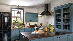 Una cocina con una isla central, armarios azules, un refrigerador negro y una pared de ladrillo.