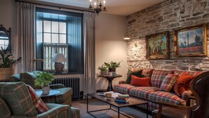 Una sala de estar acogedora con un sofá de cuadros, un sillón verde, una mesita de centro y una chimenea.