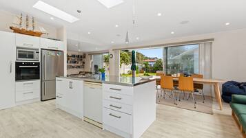 A modern kitchen with white cabinetry, a central island, and a dining area with a table and chairs.