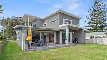 A two-story house with a covered patio area, a satellite dish, and a lawn.