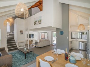 Un espacio habitable amplio con una escalera, una mesa de comedor para dos personas y una cocina equipada con electrodomésticos modernos.