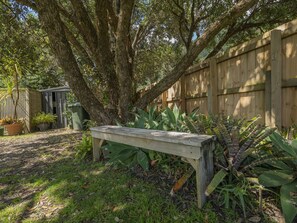 Sit and unwind in a shaded seating area surrounded by lush greenery and a small garden.