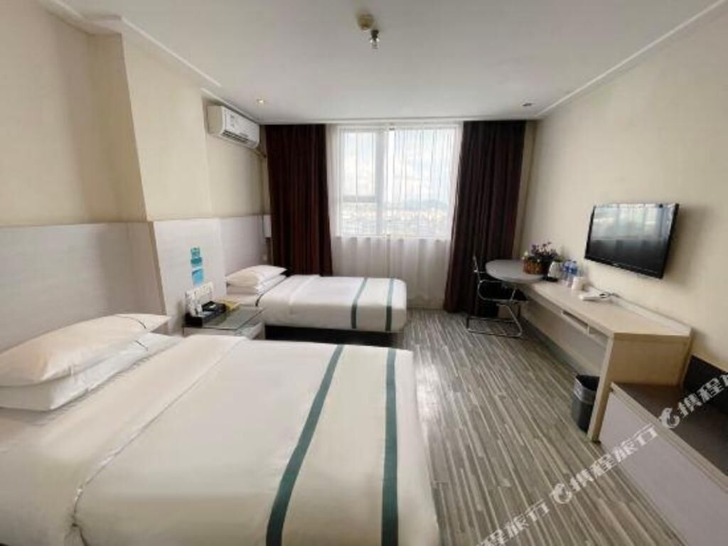 Una camera d'albergo con due letti, una scrivania con una sedia, una televisione e un condizionatore.