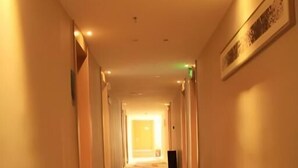 A hotel corridor with a carpeted floor, a framed picture on the wall, and a door at the end. - City Comfort Inn Laibin Liulai (Laibin)
