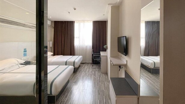 A hotel room with two beds, a desk, a chair, a flat-screen TV, and a window with curtains. - City Comfort Inn Laibin Liulai (Laibin)
