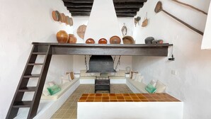 Ein rustikales Zimmer mit Schlafkoje, einem Holzbodenregal mit Keramik und einem Hängegestell für Schuhe.