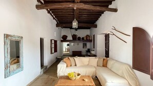 Ein gemütliches Wohnzimmer mit einer großen, winkeligen Couch, einem Holztisch und einer rustikalen Decke.