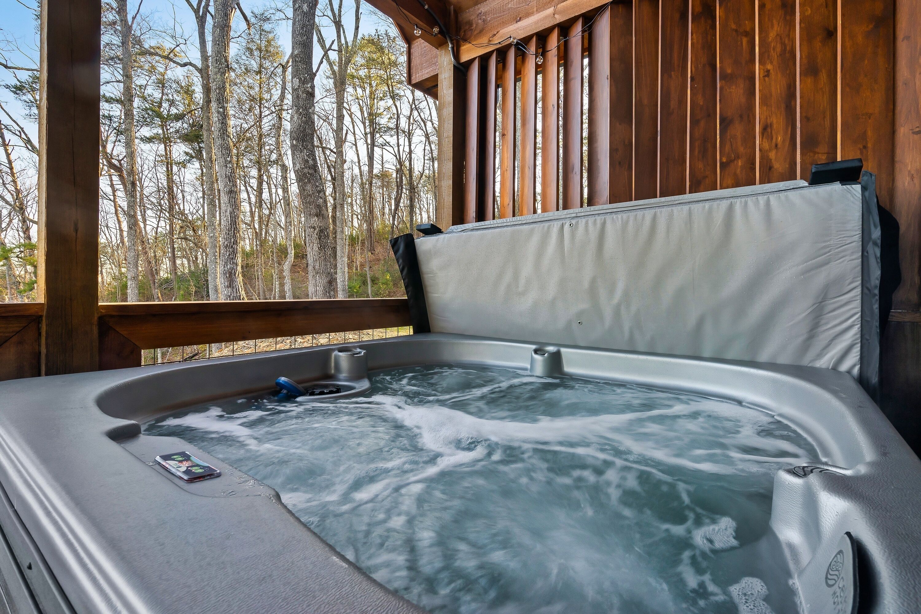 Un bain à remous avec une terrasse en bois et une vue sur les arbres.