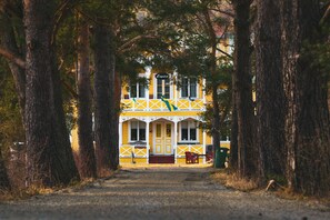 A yellow building with a porch and two doors, surrounded by trees. - Hammarstrand Budget Hotell Vandrarhem - Hostel (Hammarstrand)
